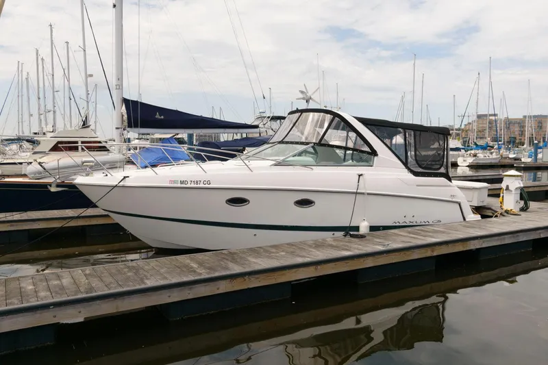 Slide: The Image of 2008 Maxum 2900 SE boat docked at a marina, surrounded by other vessels. - 1