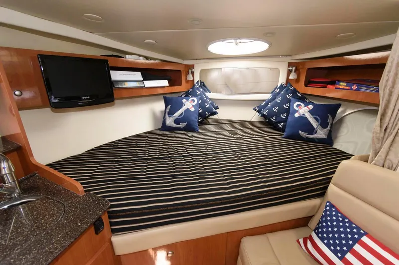 Slide: The Image of 2008 Maxum 2900 SE cabin with striped bedding, anchor-themed pillows, and a compact TV. - 12