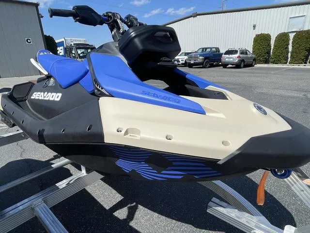 Slide: The Image of 2025 Sea-Doo Waverunner Spark Trixx, blue and beige, parked outdoors on a trailer. - 12