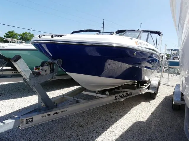Slide: The Image of 2023 Hurricane SunDeck 235 OB boat on trailer, blue and white exterior, parked outdoors. - 3