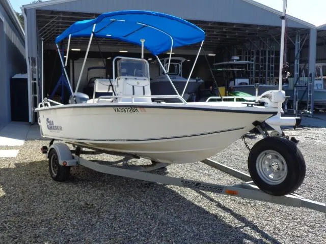 Slide: The Image of 2005 Sea Chaser 1800 RG boat on trailer with blue canopy in marina setting. - 6