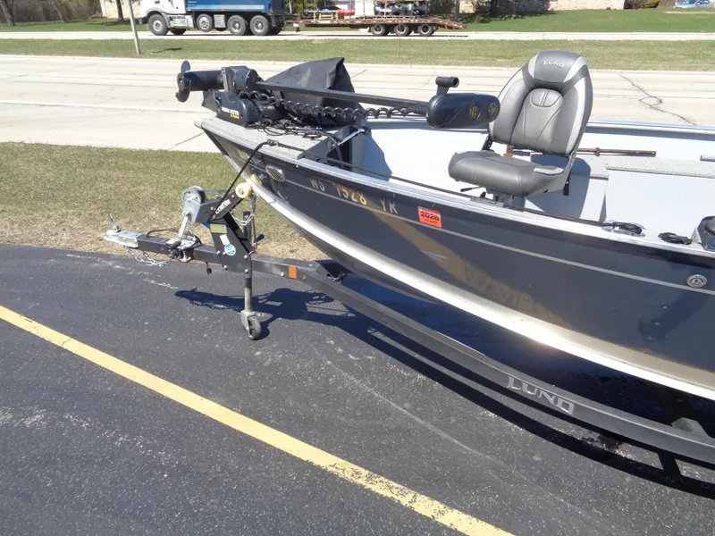 Slide: The Image of 2023 Lund 1600 Alaskan Tiller boat on trailer, parked on asphalt. - 2