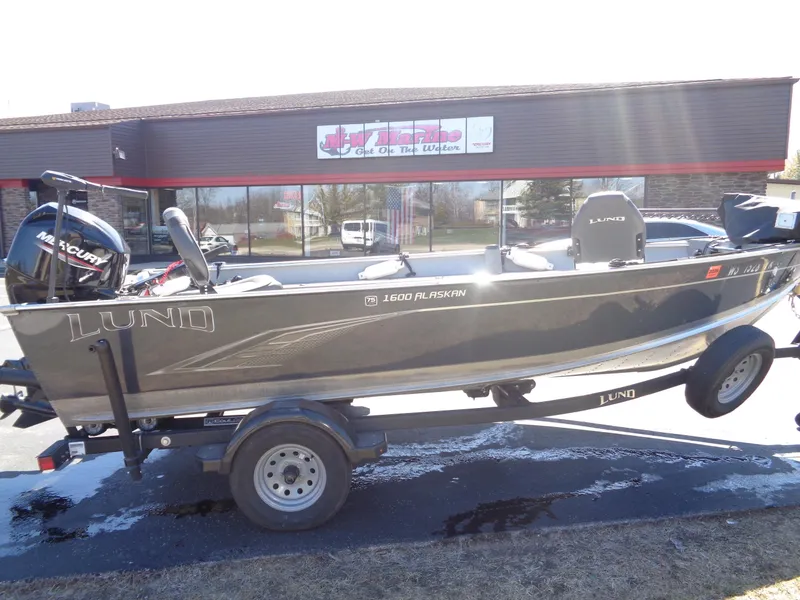 Slide: The Image of 2023 Lund 1600 Alaskan Tiller boat on trailer, parked outside a building. - 6