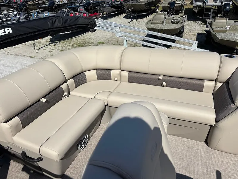 Slide: The Image of 2025 Sun Tracker Party Barge 20 DLX with beige seating in a boat showroom. - 20