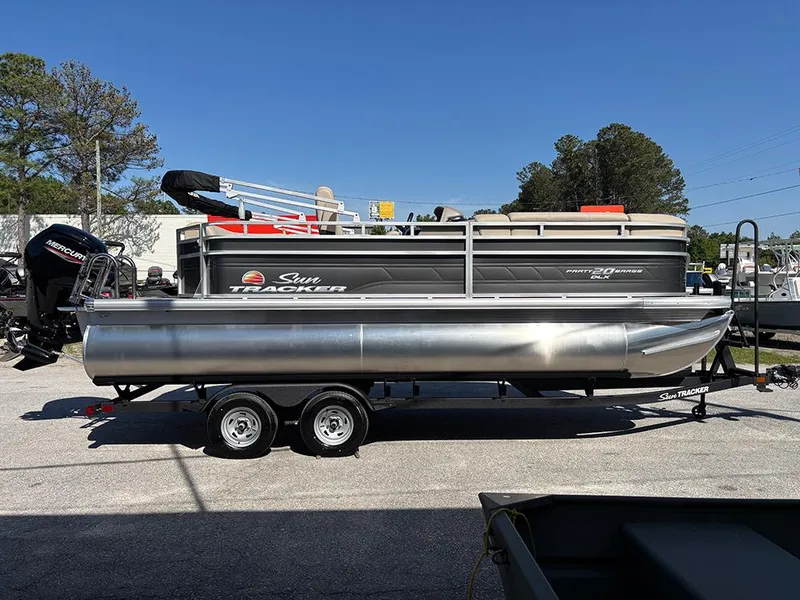 Slide: The Image of 2025 Sun Tracker Party Barge 20 DLX pontoon boat on trailer, parked outdoors. - 5
