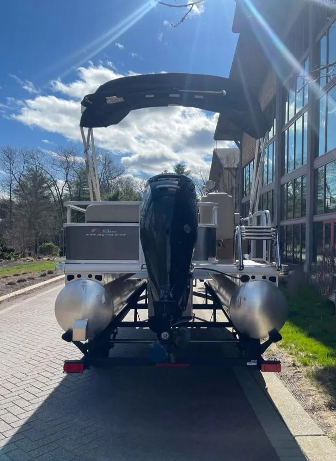 Slide: The Image of 2025 Sun Tracker Party Barge 18 DLX pontoon boat, rear view, parked outdoors. - 7