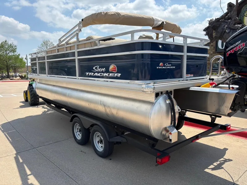 Slide: The Image of 2025 Sun Tracker Fishin' Barge 20 DLX pontoon boat on trailer, outdoor setting. - 4