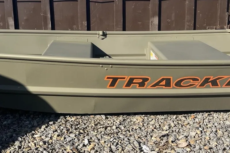 Slide: The Image of 2025 Tracker Grizzly 10 Jon boat on gravel, featuring bold orange lettering. - 1