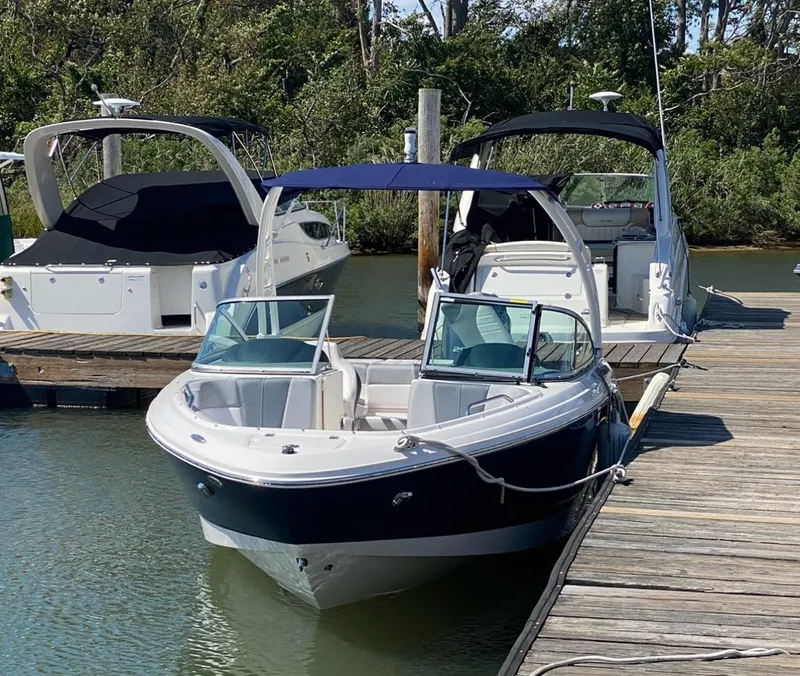 Slide: The Image of 2021 Chaparral 21 SSi OB boat docked at marina, featuring sleek design and blue canopy. - 10