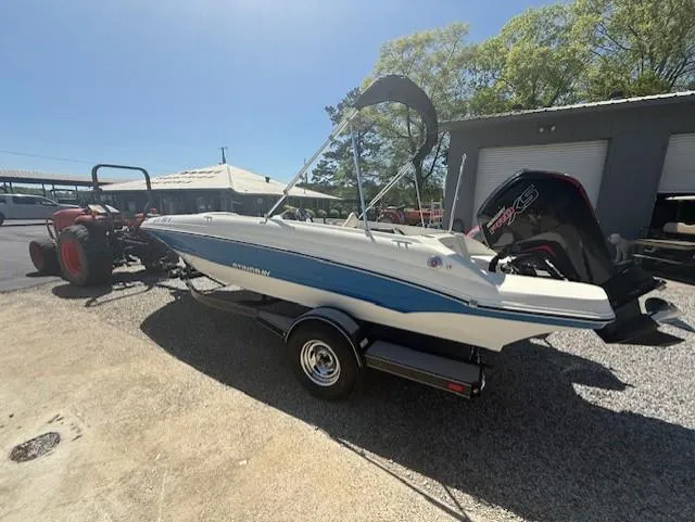 Slide: The Image of 2018 Stingray 182 SC boat on trailer, parked outdoors, with a tractor nearby. - 2