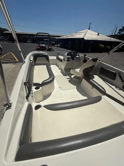 Slide: The Image of 2018 Stingray 182 SC boat interior with seating and steering wheel, parked outdoors. - 3