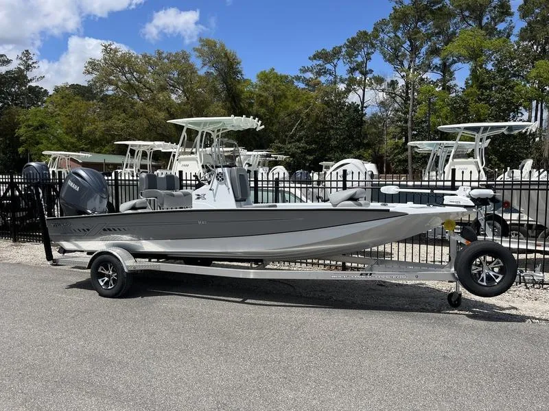 Slide: The Image of 2025 Xpress H20B boat on trailer, parked outdoors with trees and blue sky. - 0