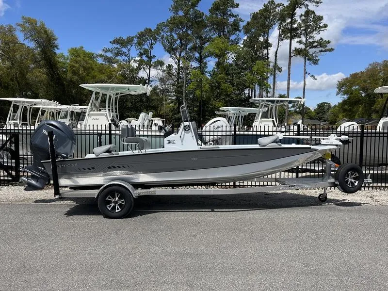 Slide: The Image of 2025 Xpress H20B boat on trailer, parked outdoors with trees in background. - 1