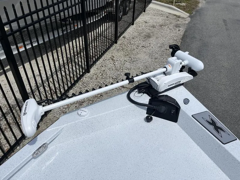 Slide: The Image of 2025 Xpress H20B boat with Minn Kota trolling motor on deck, near black fence. - 6