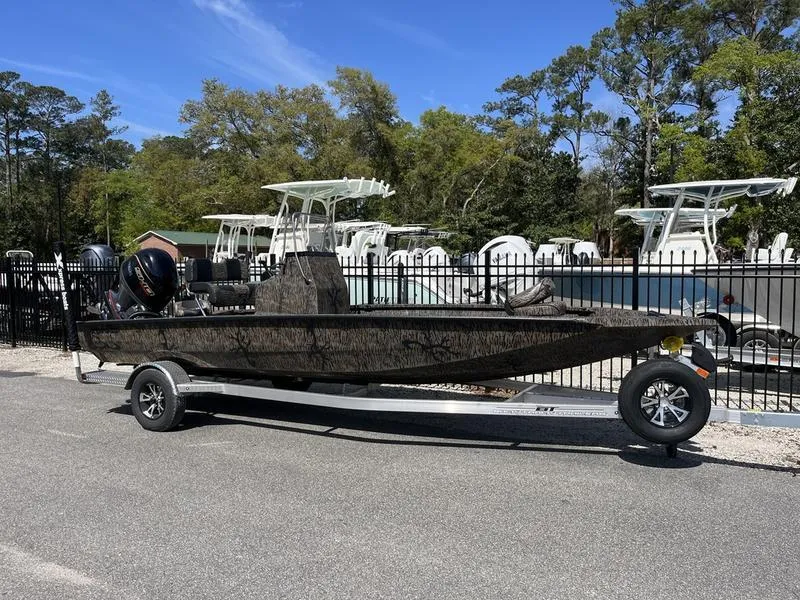 Slide: The Image of 2025 Xpress H210B boat on trailer, parked outdoors near other boats. - 0