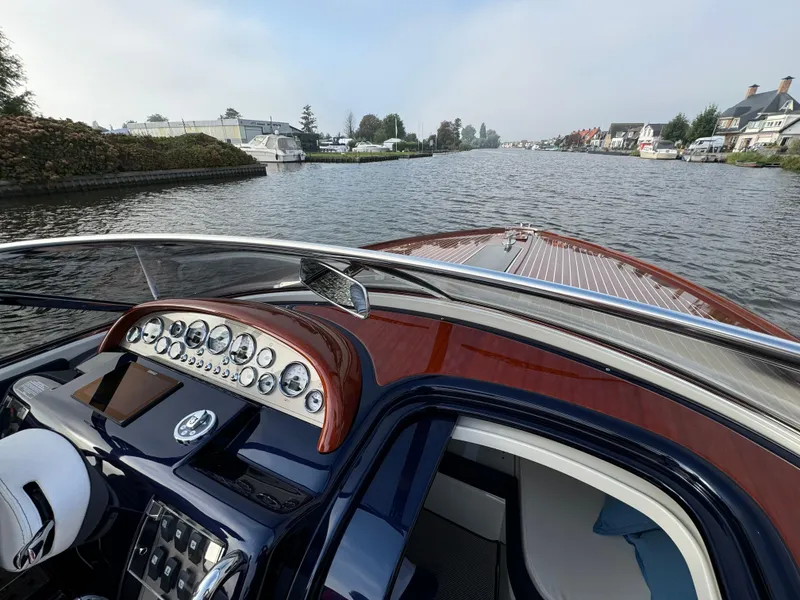 Slide: The Image of 2015 Riva Aquariva Super boat cruising on a scenic river with elegant dashboard view. - 13