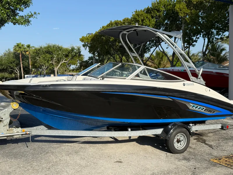Slide: The Image of 2017 Yamaha AR190 boat on trailer, black and blue design, parked outdoors. - 1