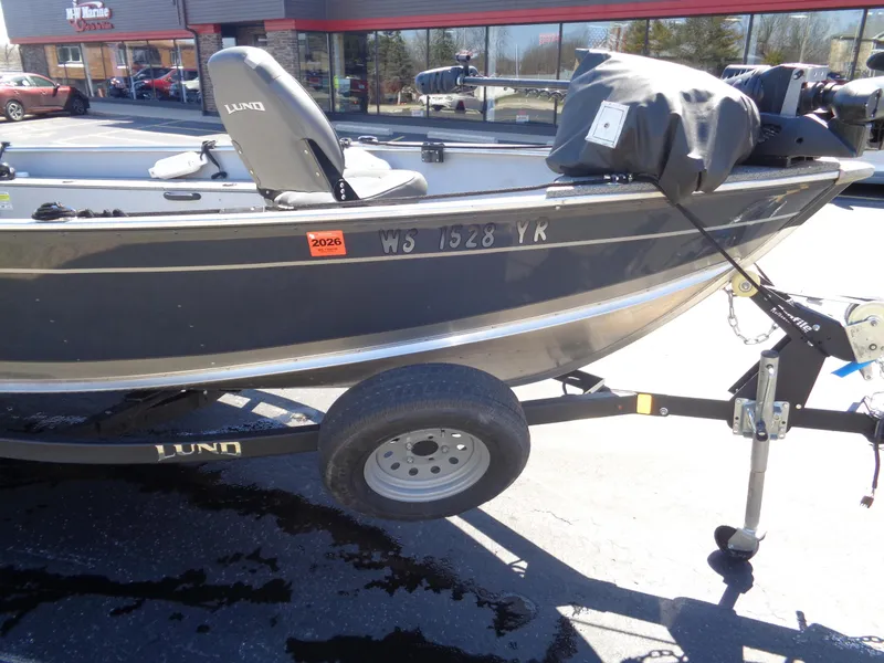 Slide: The Image of 2023 Lund 1600 Alaskan Tiller boat on trailer, parked outdoors. - 3