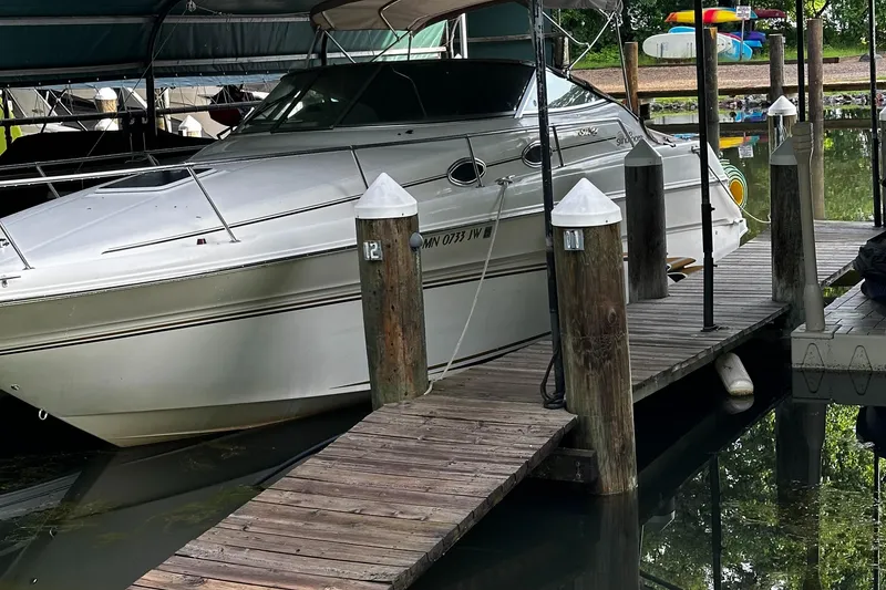 The Image of 1998 Sea Ray 270 Sundancer docked at a marina with wooden posts. - 0