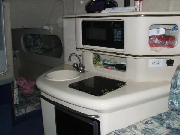 Slide: The Image of 1998 Sea Ray 270 Sundancer interior kitchenette with sink, microwave, and stove. - 3