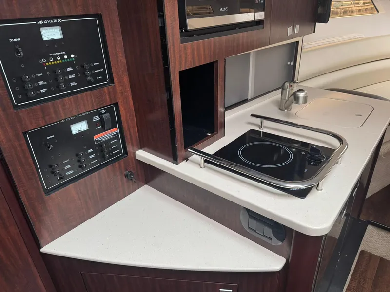 Slide: The Image of Interior of 2020 Monterey 295 Sport Yacht featuring a compact kitchen with stove and control panels. - 22