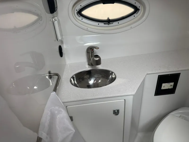 Slide: The Image of 2020 Monterey 295 Sport Yacht bathroom with sink, porthole, and towel holder. - 30
