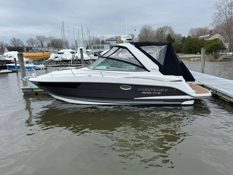 The Image of 2020 Monterey 295 Sport Yacht docked in a marina, featuring sleek design and black canopy. - 5