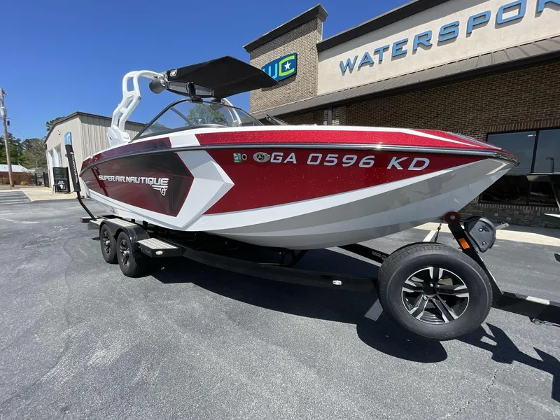 Slide: The Image of 2017 Nautique Super Air G23 boat in red and white, parked outside a watersports store. - 13