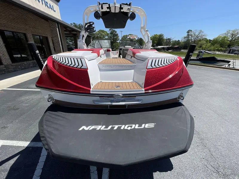 Slide: The Image of 2017 Nautique Super Air G23 boat, red and white, parked outdoors, rear view. - 15