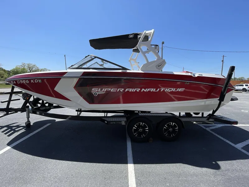Slide: The Image of 2017 Nautique Super Air G23 boat on trailer, red and white design, parked outdoors. - 2