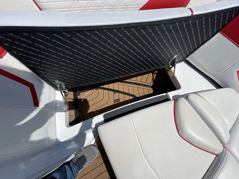 Slide: The Image of 2017 Nautique Super Air G23 interior with open storage compartment, featuring white and red seating. - 33