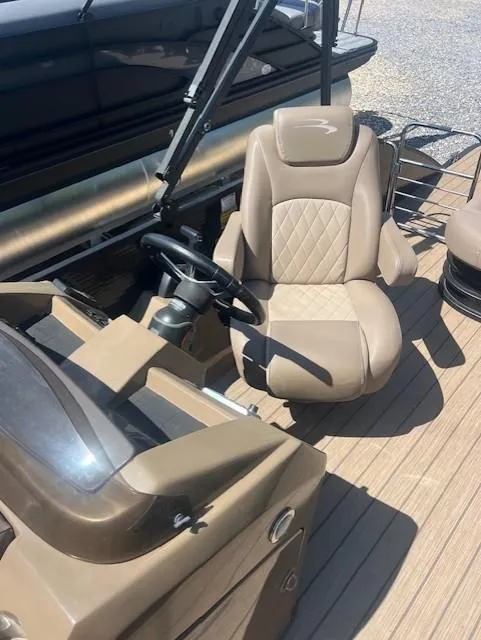Slide: The Image of 2017 Bennington 24 SSBXP boat interior with tan captain's chair and steering console. - 2