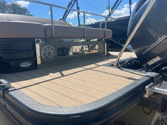 Slide: The Image of 2017 Bennington 24 SSBXP pontoon boat deck with seating and motor, under a clear blue sky. - 8
