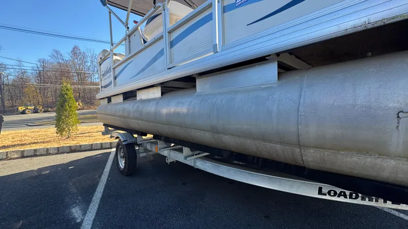 Slide: The Image of 2003 Godfrey Sweet Water pontoon boat on trailer in parking lot. - 2