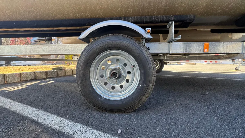 Slide: The Image of Trailer wheel of a 2003 Godfrey Sweet Water boat on asphalt. - 27
