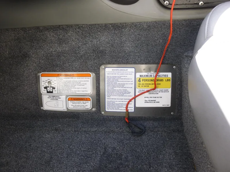 Slide: The Image of 2016 Tracker Pro Team 195 TXW boat capacity and warning labels on carpeted interior. - 10
