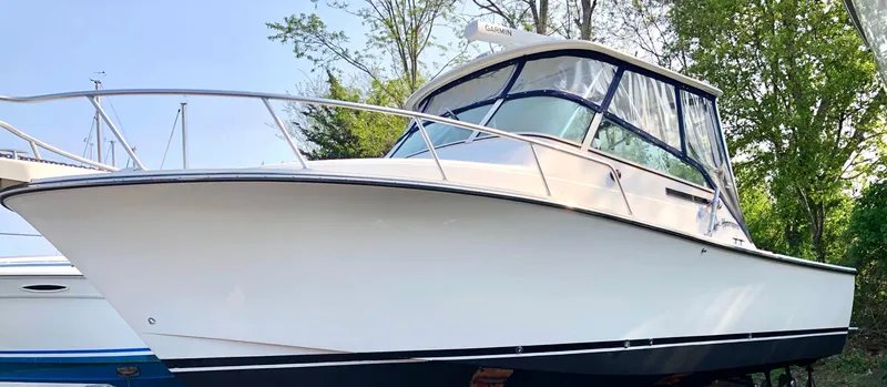 The Image of 1999 Henriques 28 Express Sportfish boat with canopy, docked outdoors. - 0