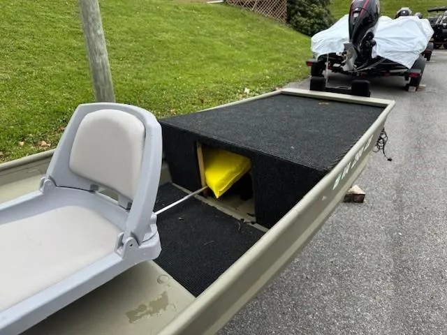 Slide: The Image of 2024 Tracker Grizzly 1436 Jon boat with seating and storage on a paved surface. - 5