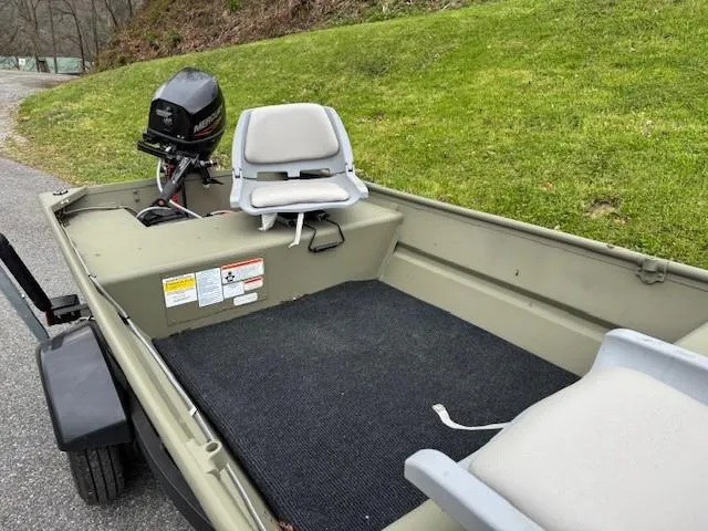Slide: The Image of 2024 Tracker Grizzly 1436 Jon boat with motor and seating, parked on roadside. - 6