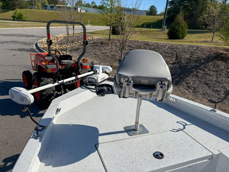Slide: The Image of 2023 Xpress H22 boat with a mounted seat and trolling motor, parked near a tractor. - 13