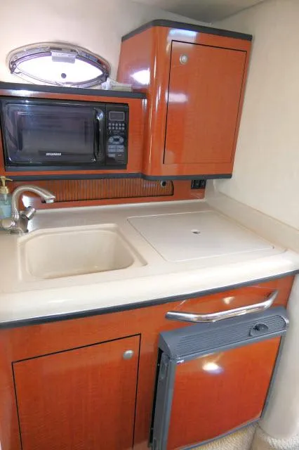 Slide: The Image of 2005 Sea Ray 280 Sundancer kitchenette with sink, microwave, and storage cabinets. - 11