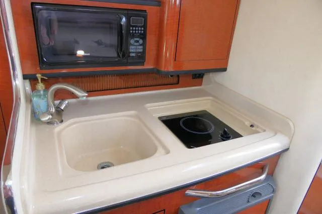 Slide: The Image of 2005 Sea Ray 280 Sundancer galley with sink, stove, and microwave. - 13