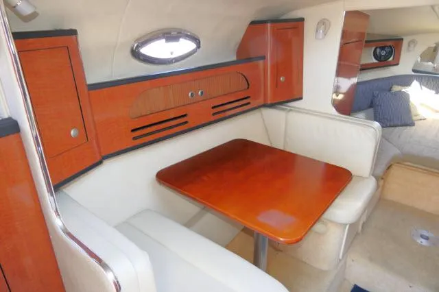 Slide: The Image of Interior of 2005 Sea Ray 280 Sundancer with wooden table and white seating. - 3