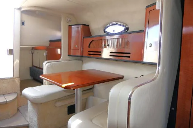 Slide: The Image of Interior of 2005 Sea Ray 280 Sundancer with wooden table and seating area. - 8