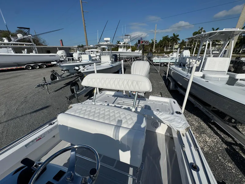 Slide: The Image of 2025 Contender 23 Bay boat with white seating, displayed in a marina under clear skies. - 17