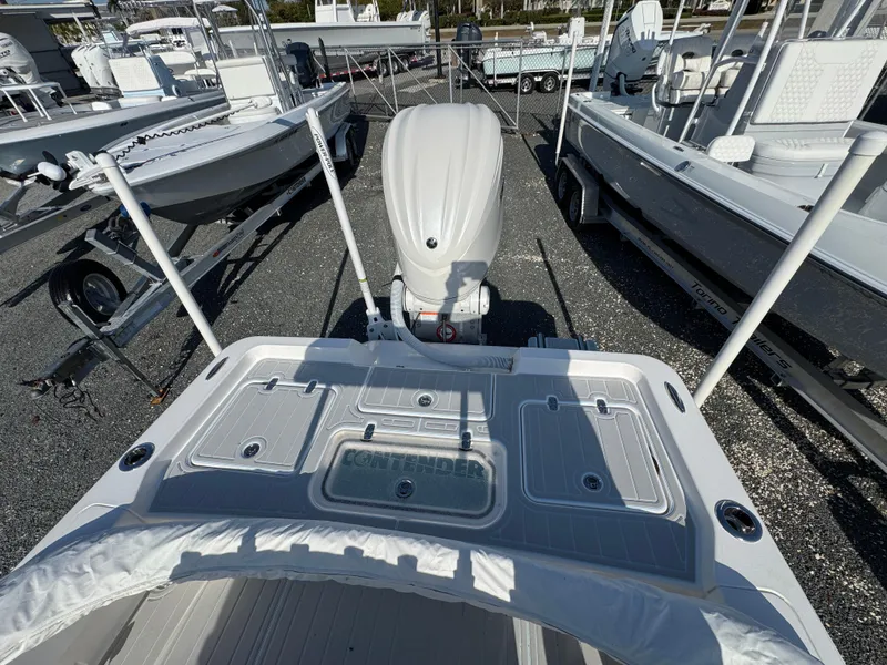 Slide: The Image of 2025 Contender 23 Bay boat with outboard motor, docked among other boats. - 19