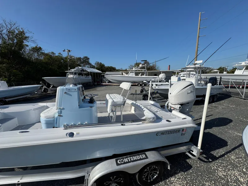 Slide: The Image of 2025 Contender 23 Bay boat on trailer in marina under clear blue sky. - 6