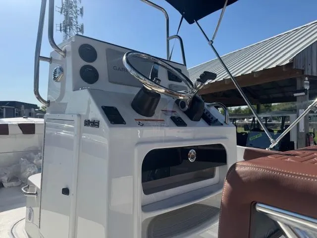 Slide: The Image of 2025 Parker 18SE Center Console boat with modern steering and controls, docked under a canopy. - 8