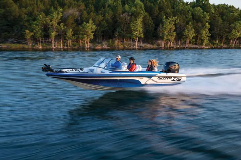 Slide: The Image of 2020 Nitro Z19 Sport boat speeding on a lake with passengers, surrounded by trees. - 18