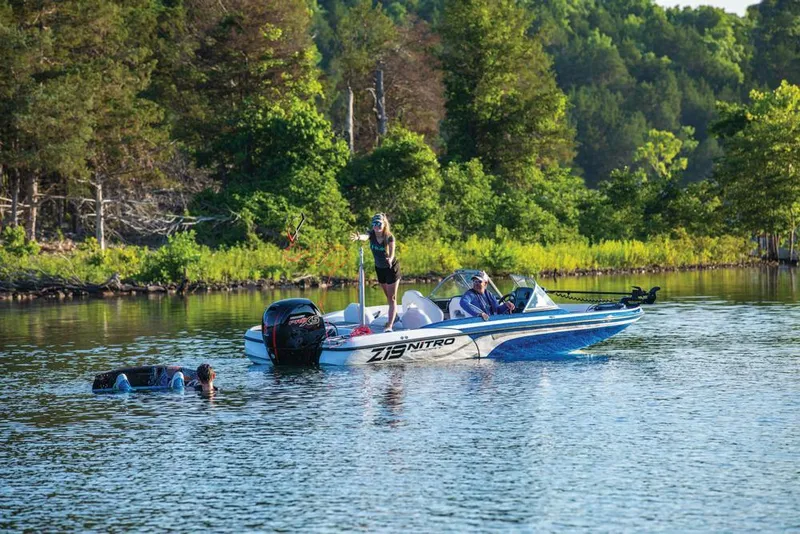 Slide: The Image of 2020 Nitro Z19 Sport boat on a scenic lake with swimmers nearby. - 19